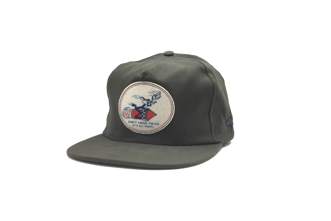 Olive green cotton twill The Ampal Creative - Don’t Think Twice Strapback / Olive baseball cap featuring a vintage circular patch of a cartoon character riding a rocket with the text Dont think twice (its all right).