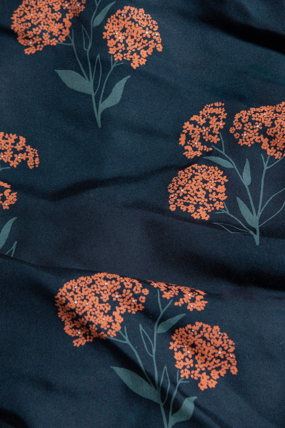 The Mila Cropped Shirt / Wildflower by Bridge & Burn is a dark blue, sustainable modal shirt with an orange wildflower print and scattered green stems.