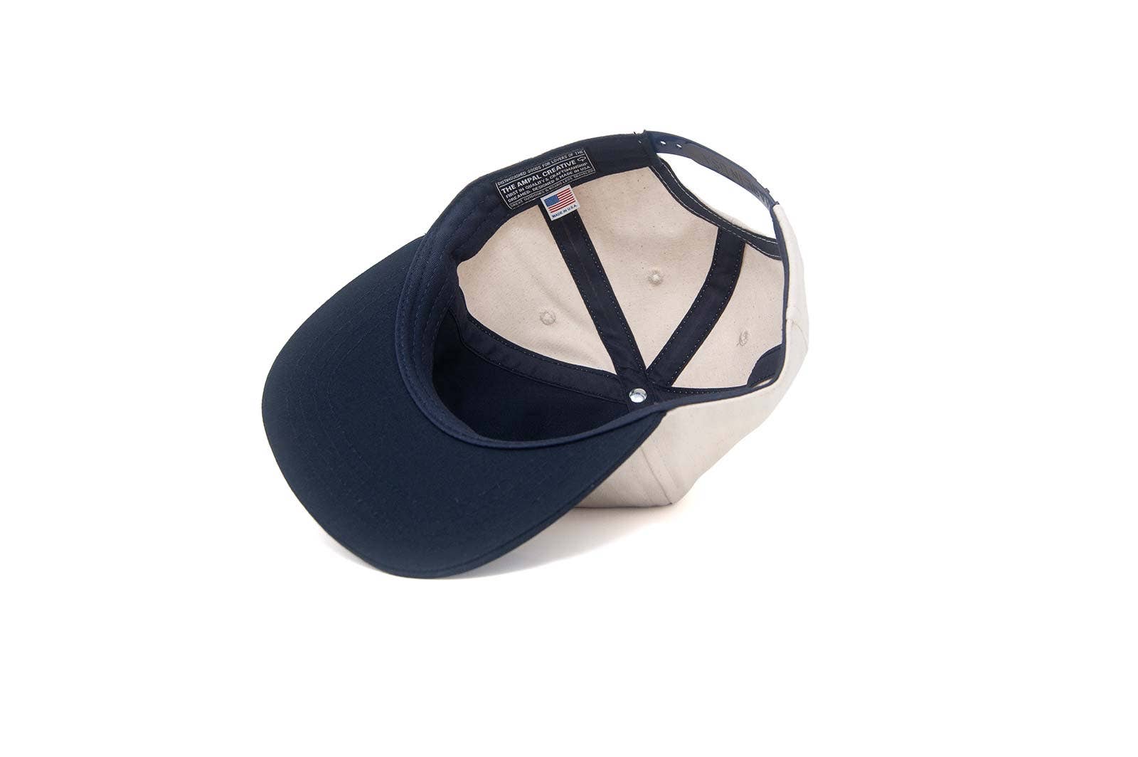 The Ampal Creative - Don't Think Twice Snapback in navy is pictured upside down, revealing its classic patch, interior labels, and detailed stitching against a plain white background.