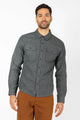 A man wearing the Bridge & Burn Cole Slim Shirt in Stone, featuring chest pockets, and brown pants stands against a plain white background.