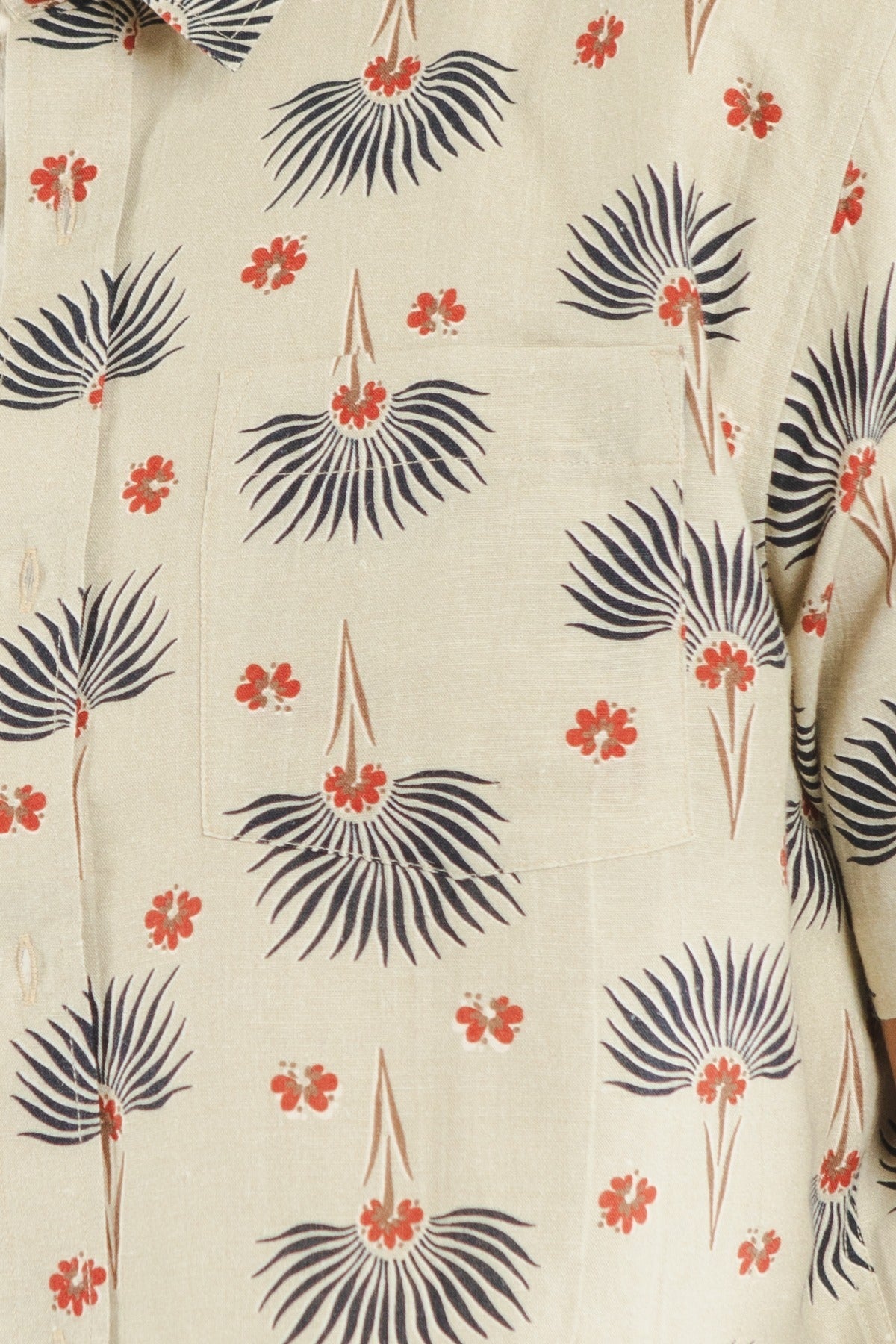 The Harbor Slim Shirt / Aloha Floral by Bridge & Burn is a beige slim fit shirt with a chest pocket, adorned with black palm-like leaves and small red floral designs. Made from a linen-cotton blend, it features visible buttons on the left side.