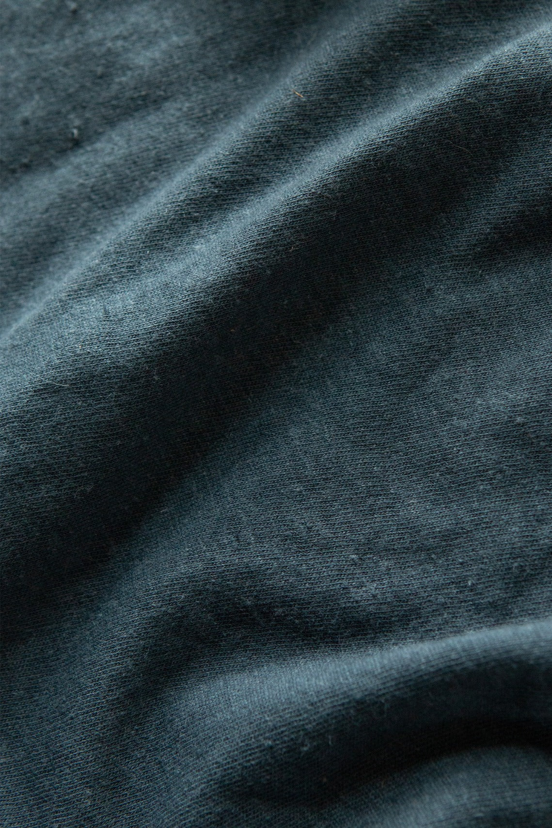 Close-up of the soft, textured fabric and gentle creases on the Bridge & Burn Organic Hemp Pocket Tee in Storm Blue, crafted from sustainable organic cotton hemp.