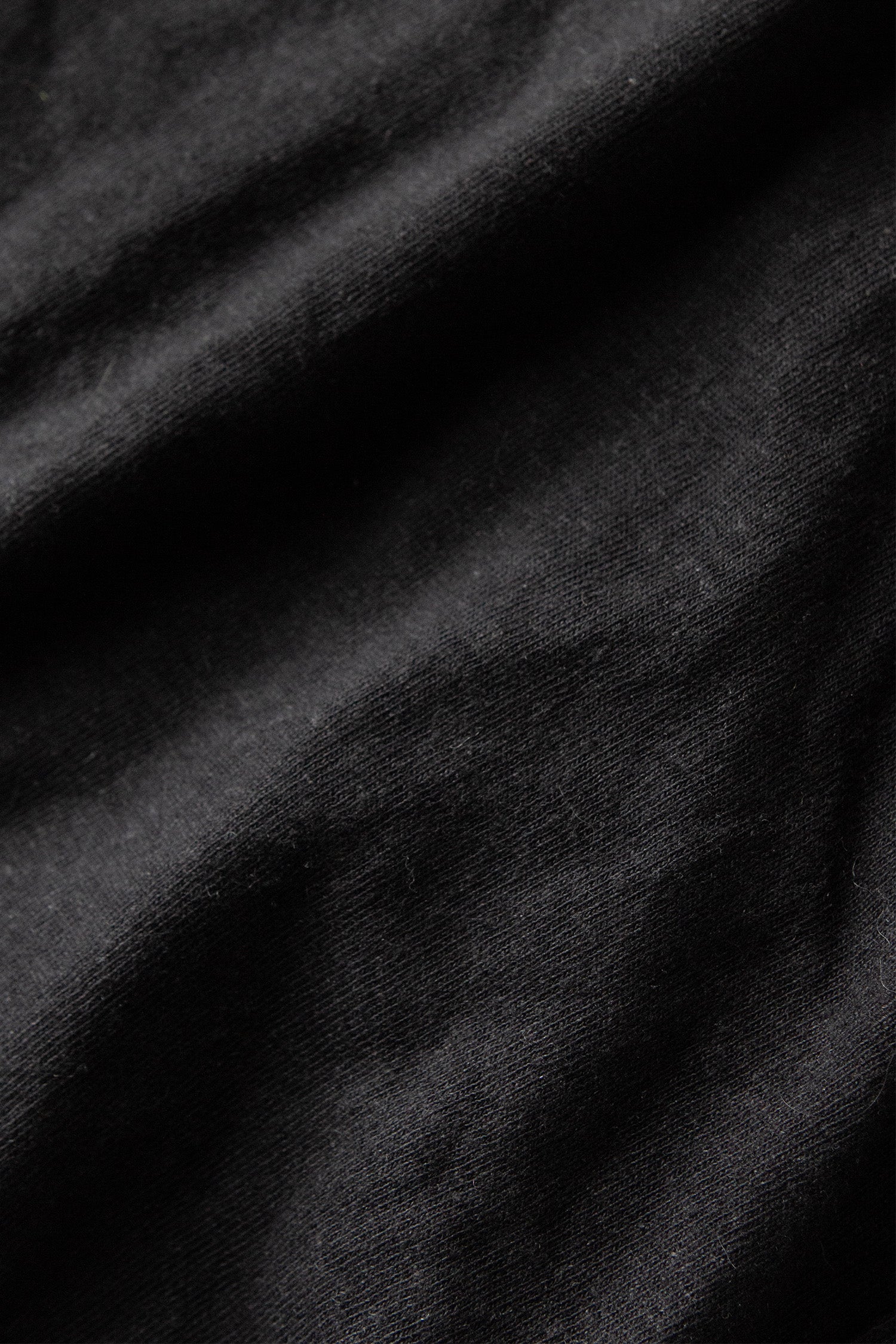 Close-up of Bridge & Burn's Organic Hemp Boxy Tee in Washed Black, highlighting the soft texture and subtle folds of its sustainable midweight jersey fabric.