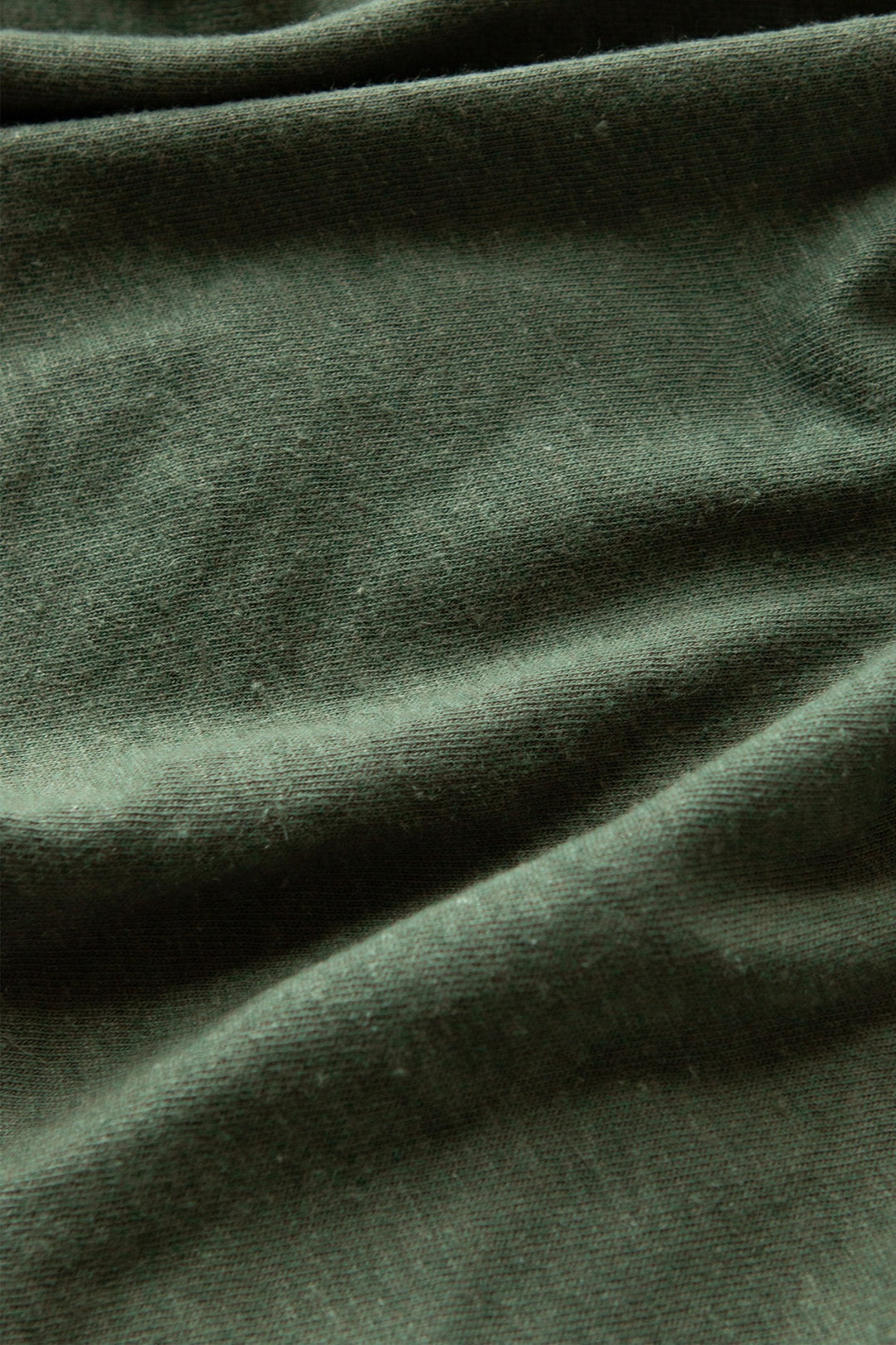 Close-up of Cypress green fabric with soft folds and subtle texture—ideal for the Organic Hemp Boxy Tee by Bridge & Burn, a sustainable women's t-shirt with vintage style.