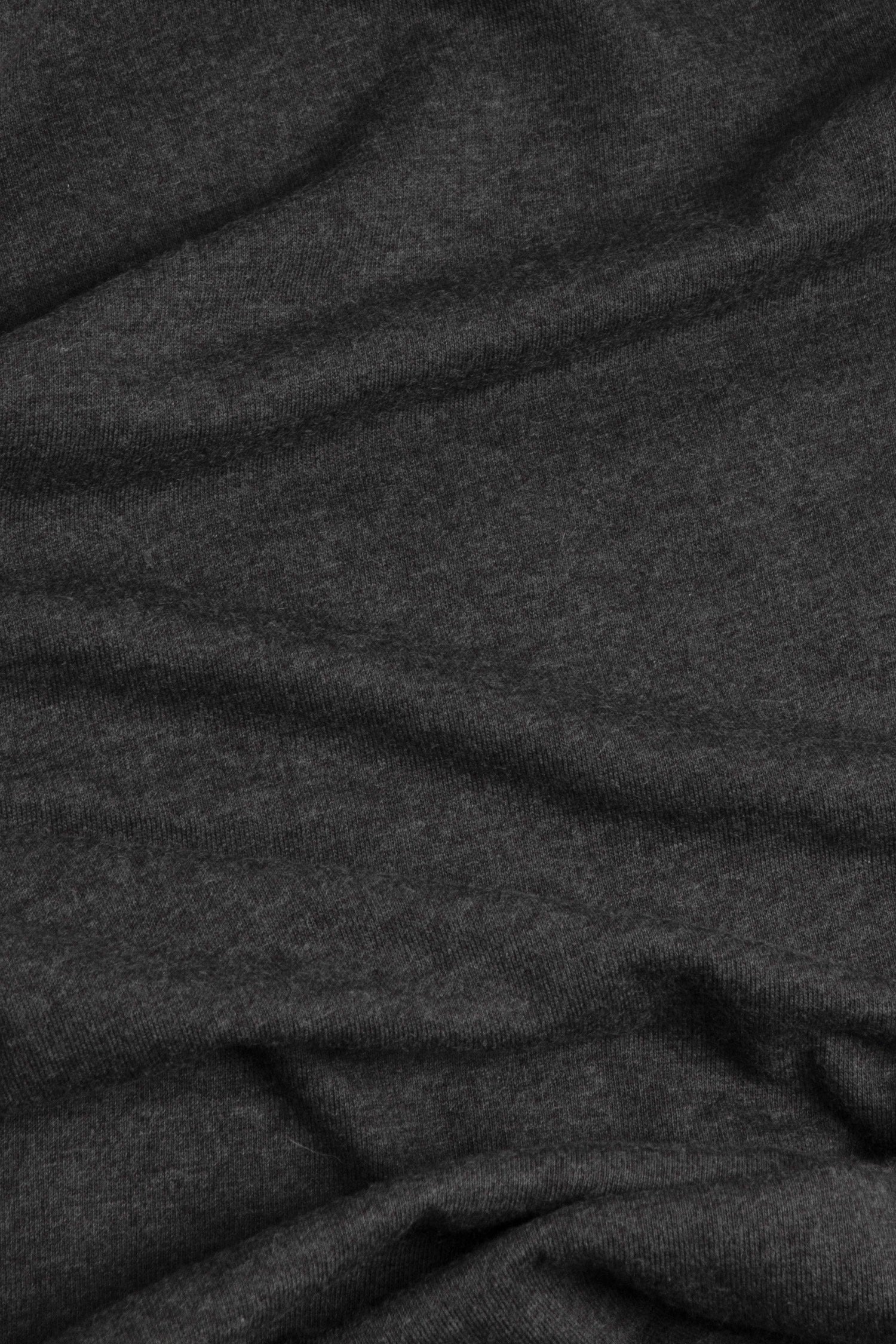 A close-up of the soft, charcoal fabric from Bridge & Burn's Women's Arch Tee features subtle folds and gentle creases across its surface.