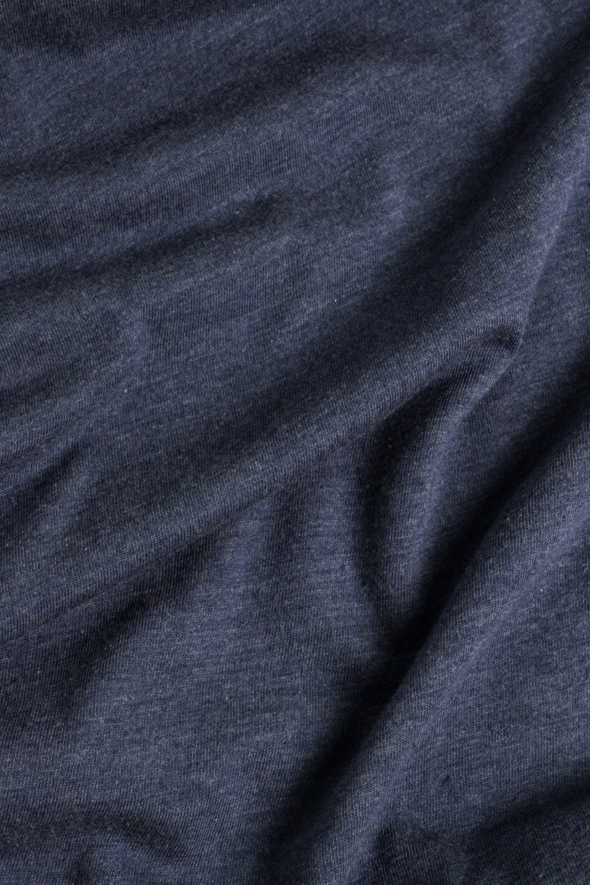A close-up of the soft, slightly wrinkled navy fabric from the Bridge & Burn Women's Peace In Plants Tee, highlighting its texture and gentle folds.
