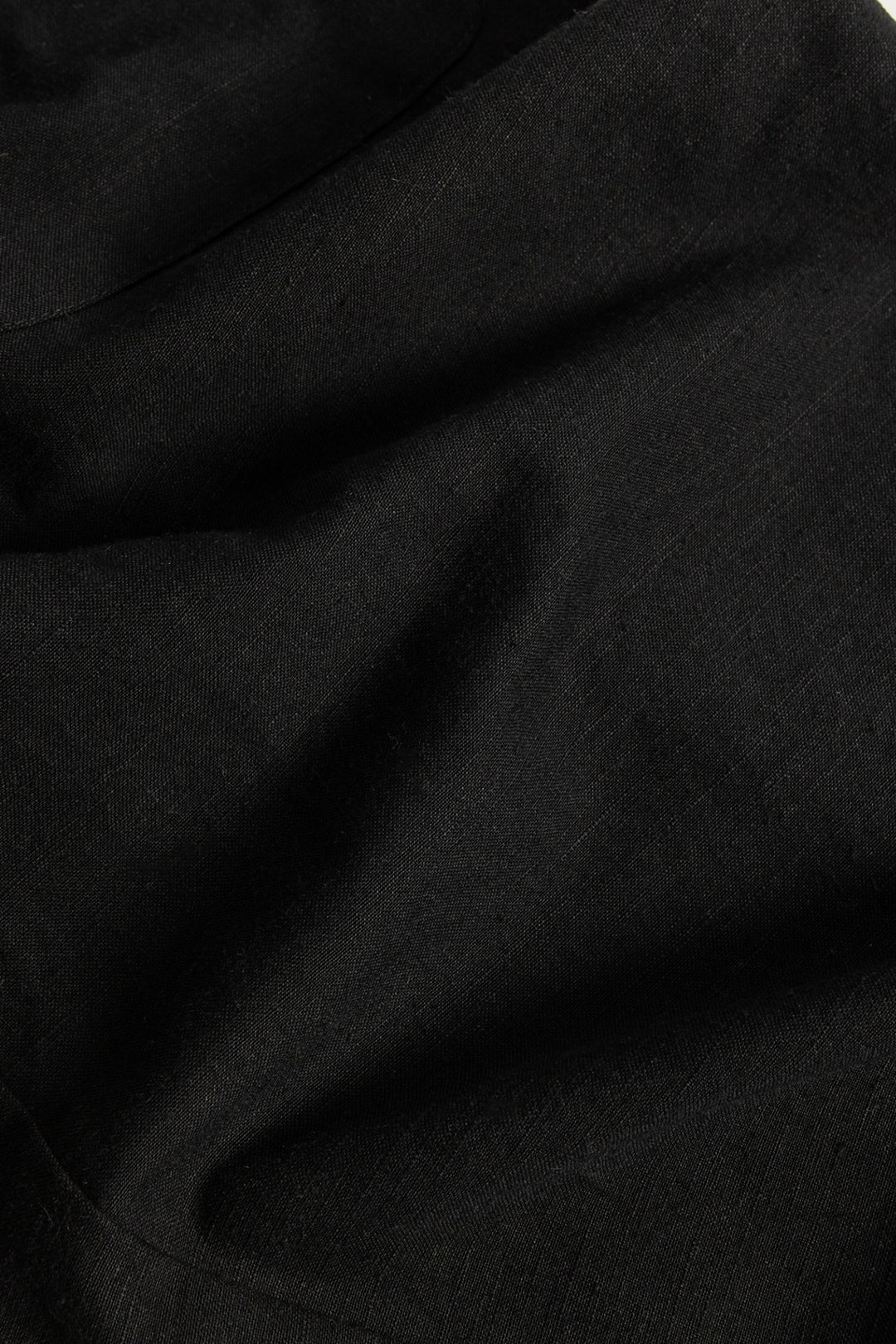 A close-up view of black linen-cotton blend fabric reveals its textured weave and slight sheen, highlighting the material used for Bridge & Burn's Edie Overall in Black—a perfect choice for crafting wide leg overalls with adjustable straps.