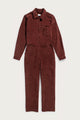 The Bridge & Burn Faye Jumpsuit in Dark Red Pinwale, a women’s corduroy style with long sleeves, collar, chest and side pockets, and workwear-inspired details, is laid flat on a plain white background.