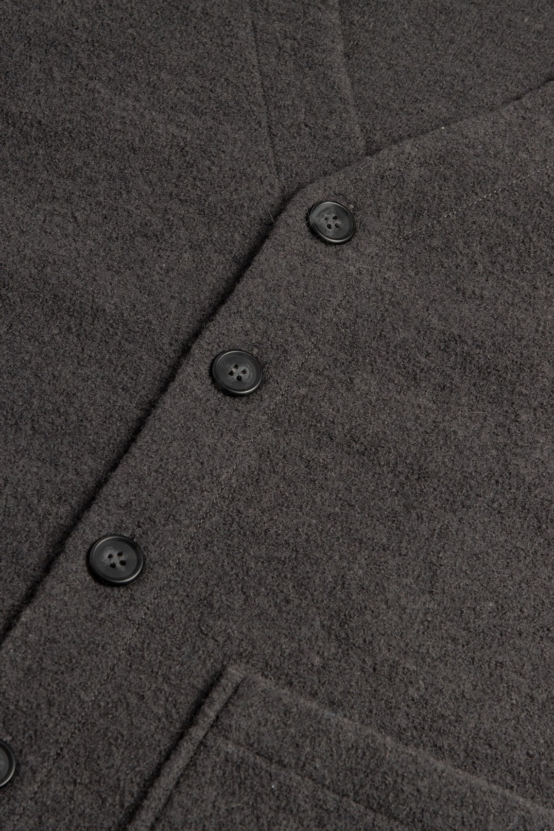Close-up of the Bridge & Burn Whit Cardigan in Charcoal shows soft, textured boiled wool, four black buttons, and a partial patch pocket near the hem.