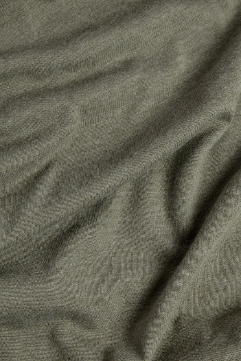 A close-up of the Women's Flown Tee in Olive by Bridge & Burn shows soft folds and gentle texture, casting subtle shadows and highlights—an eco-friendly shirt made from organic cotton.