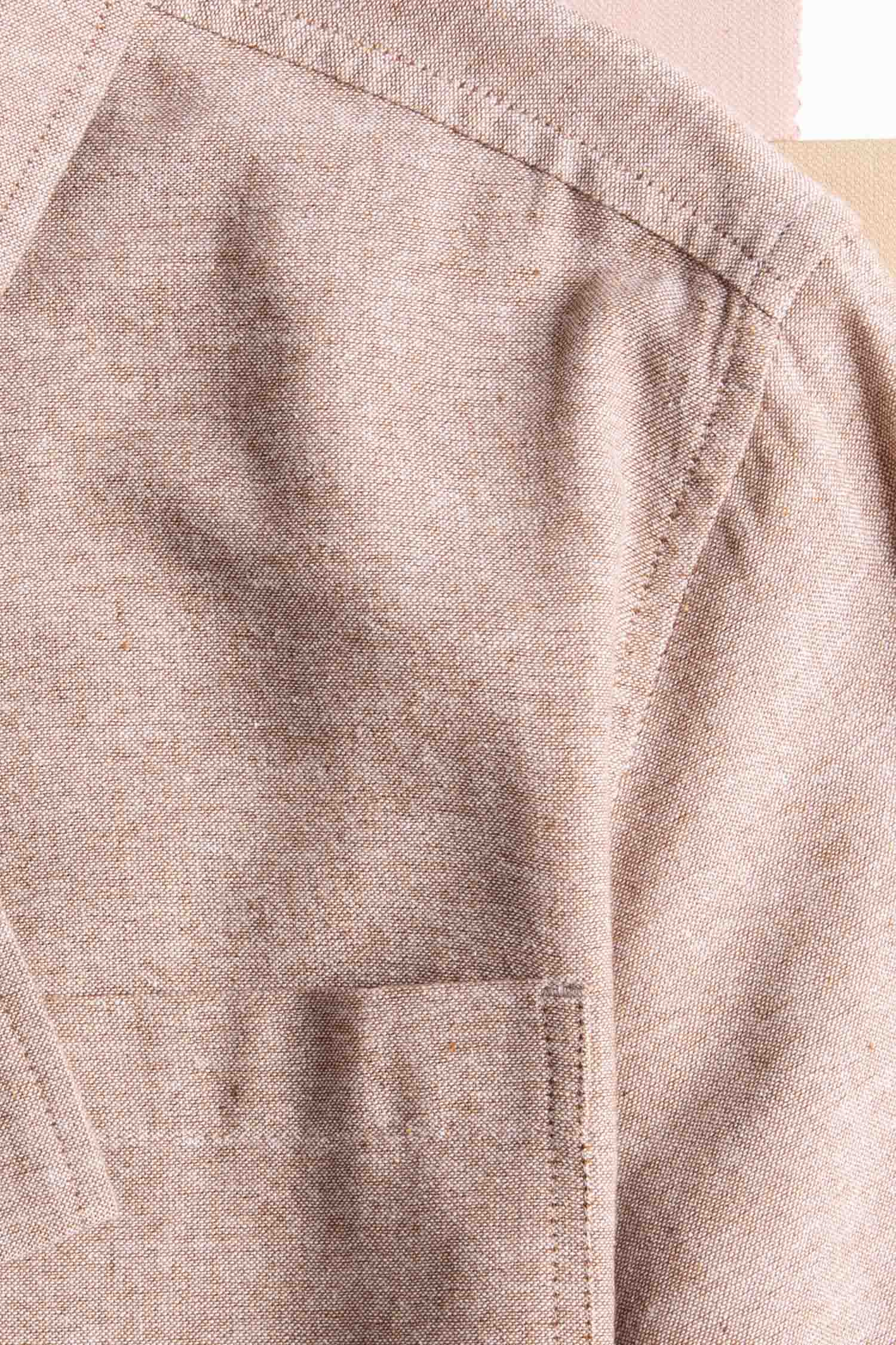 Close-up of the Bridge & Burn Bea Shirt in rust chambray, showcasing the shoulder, sleeve seam, pocket, and collar—sustainably crafted and set against a neutral background.