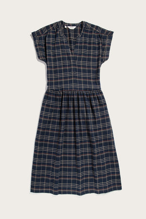 The Bridge & Burn Ira Dress in Dusk Herringbone Plaid is a navy pullover with short sleeves, v-neckline, gathered waist, and beige-red plaid. Made from recycled cotton for sustainability. Shown laid flat on a white background.