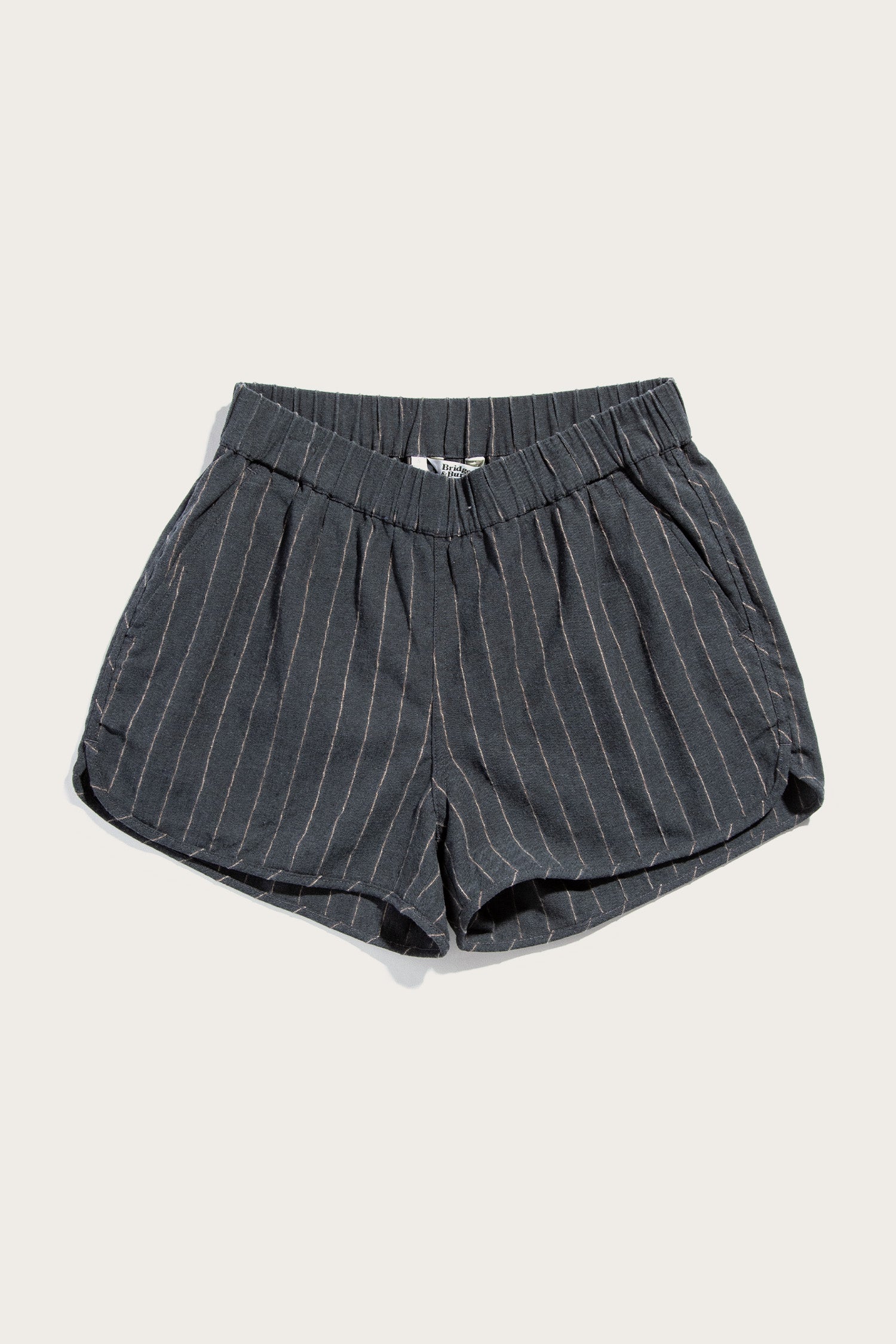 The Bridge & Burn Luca Track Short in Charcoal Stripe features thin white pinstripes, an elastic waistband, and side pockets. Crafted from a cotton-linen blend, these summer shorts are shown laid flat against a plain light background.