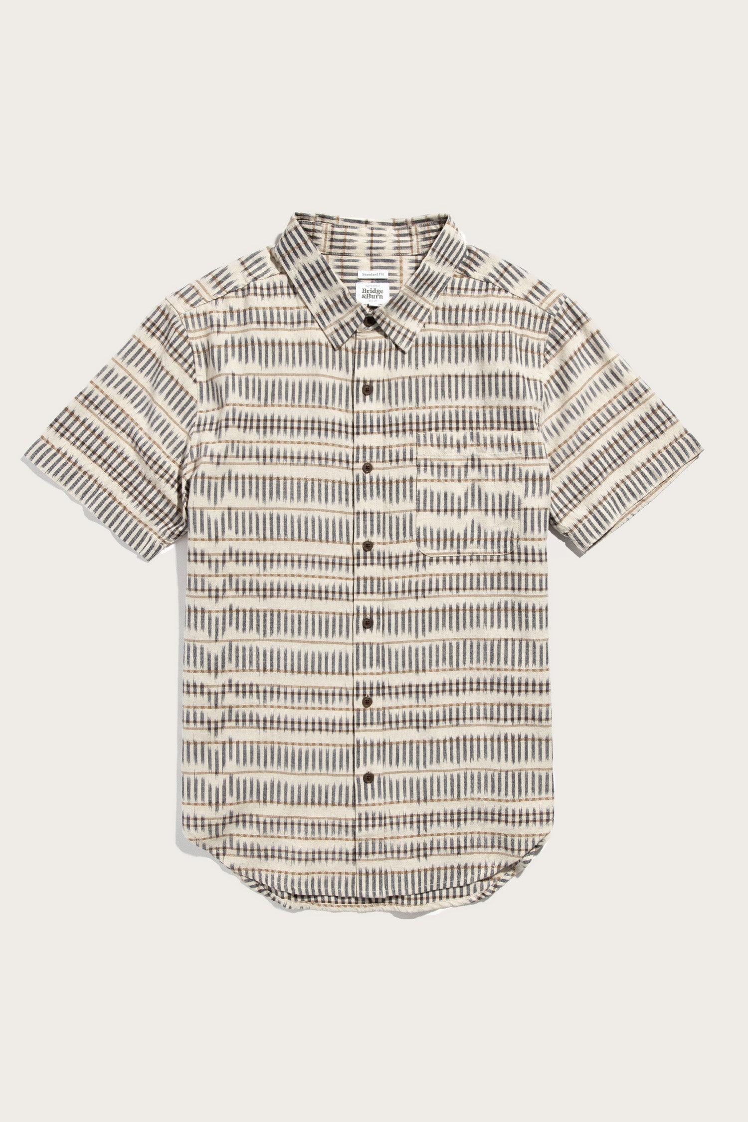 The Malcolm Shirt by Bridge & Burn features a sustainable, organic cotton short sleeve button-up with a collar and single chest pocket, showcasing a brown, black, and white Mushroom Ikat Stripe geometric pattern.