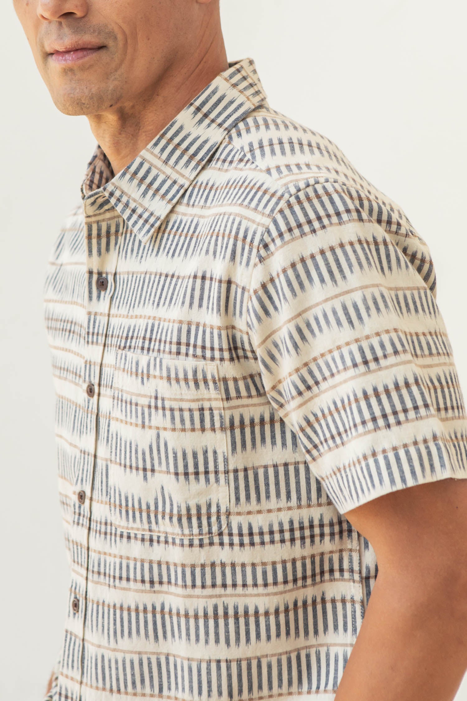A person is shown from the chest up at an angle, wearing the Bridge & Burn Malcolm Shirt in Mushroom Ikat Stripe against a light background.