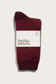 A single Helix Sock in burgundy from Bridge & Burn is folded and wrapped with a white brand label, set against a plain light background.
