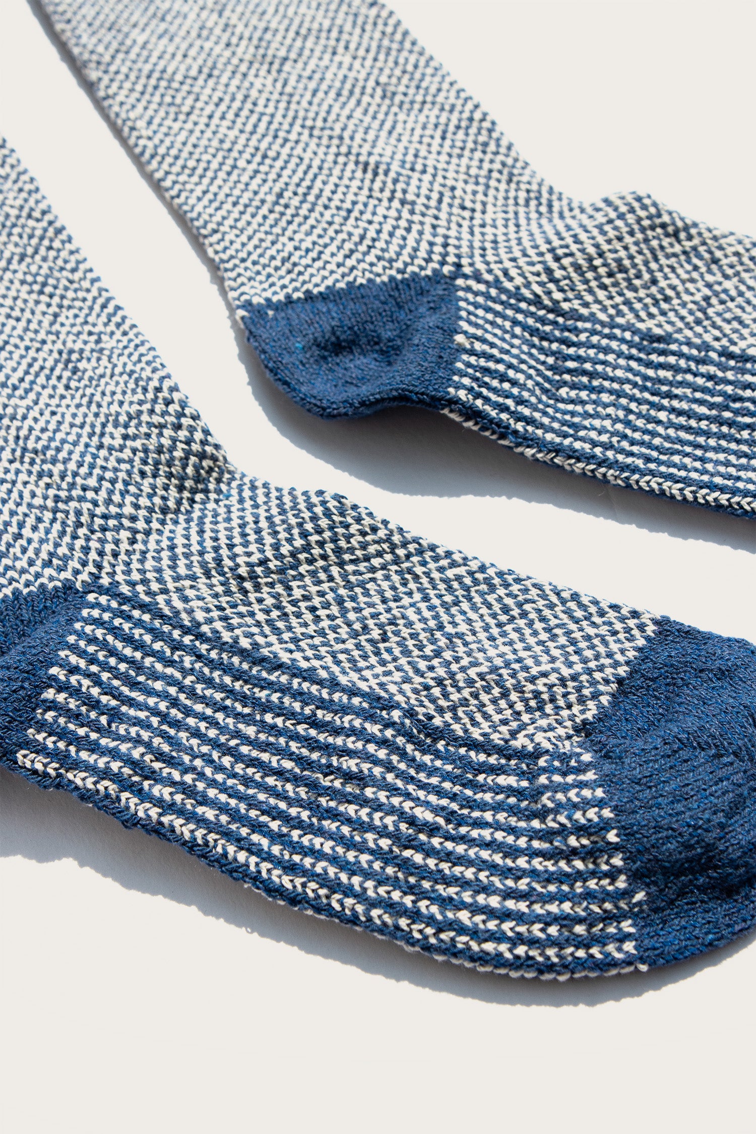 A close-up of the Bridge & Burn Helix Sock in Navy, featuring a white and blue speckled pattern with solid navy heels and toes, laid out flat on a light background.