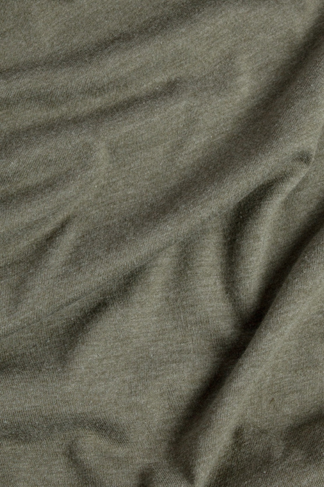 A close-up of the olive Women's Ladera Tee by Bridge & Burn, crafted from organic cotton and recycled plastic bottles—showcasing its soft texture and natural folds.