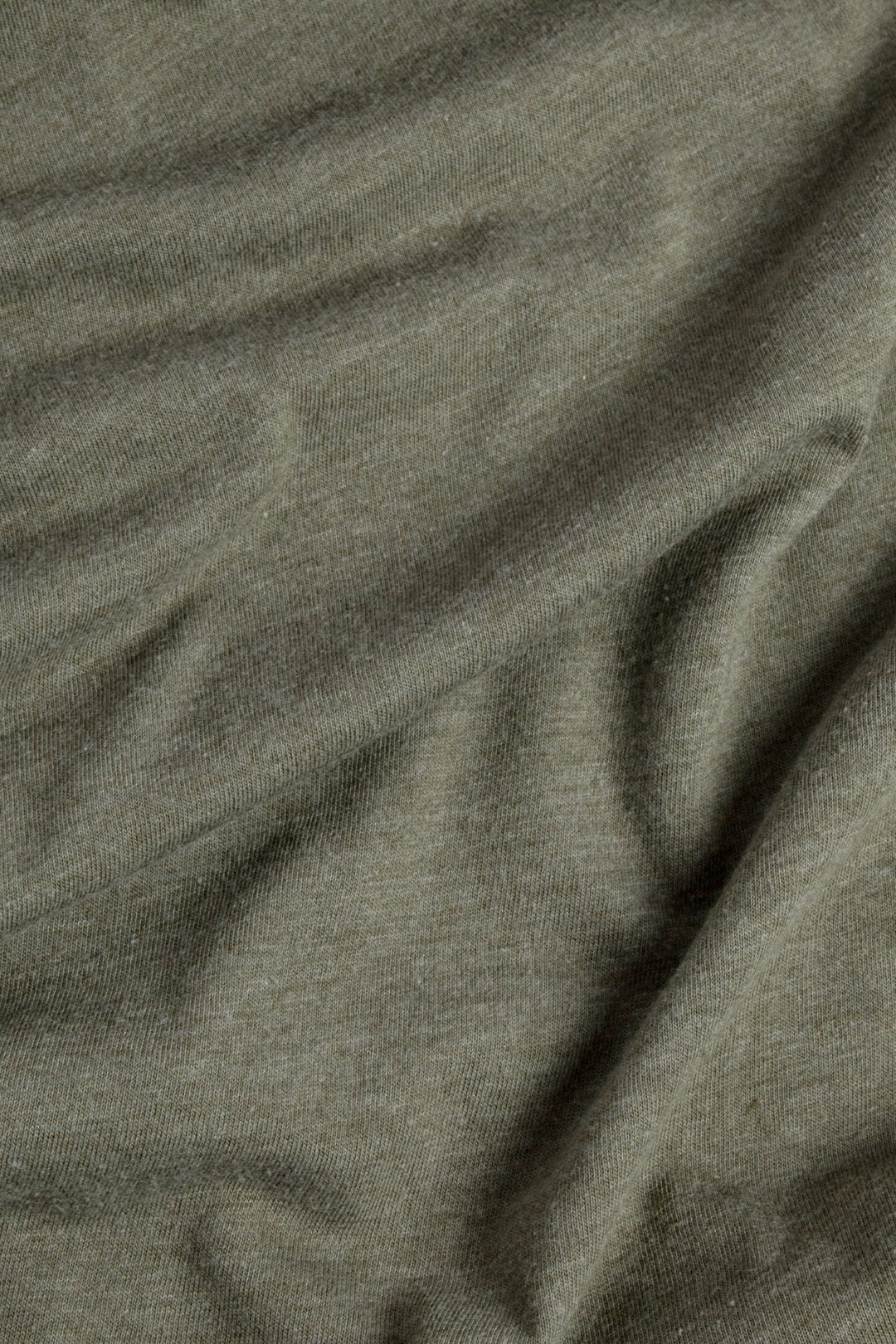 A close-up of the olive Women's Ladera Tee by Bridge & Burn, crafted from organic cotton and recycled plastic bottles—showcasing its soft texture and natural folds.