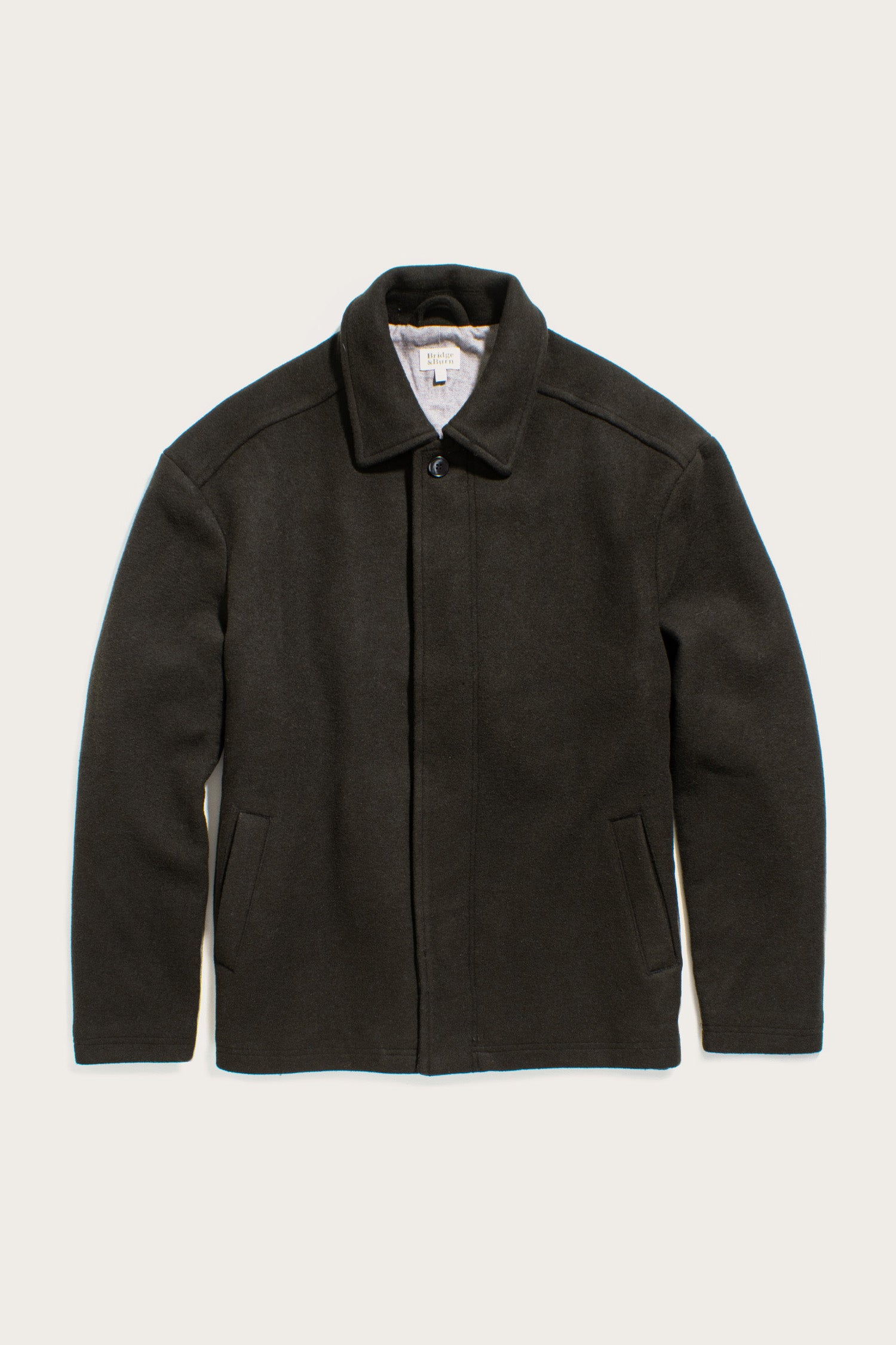 The Bridge & Burn Clive Car Coat in Deep Sage features a collar, long sleeves, front pockets, and a concealed front closure for cold-weather comfort, shown laid flat on a light background.