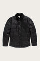 The Bridge & Burn Holman Quilted Jacket in black waxed canvas features a quilted design, button-up front, long sleeves, and a soft collar, shown on a light background.