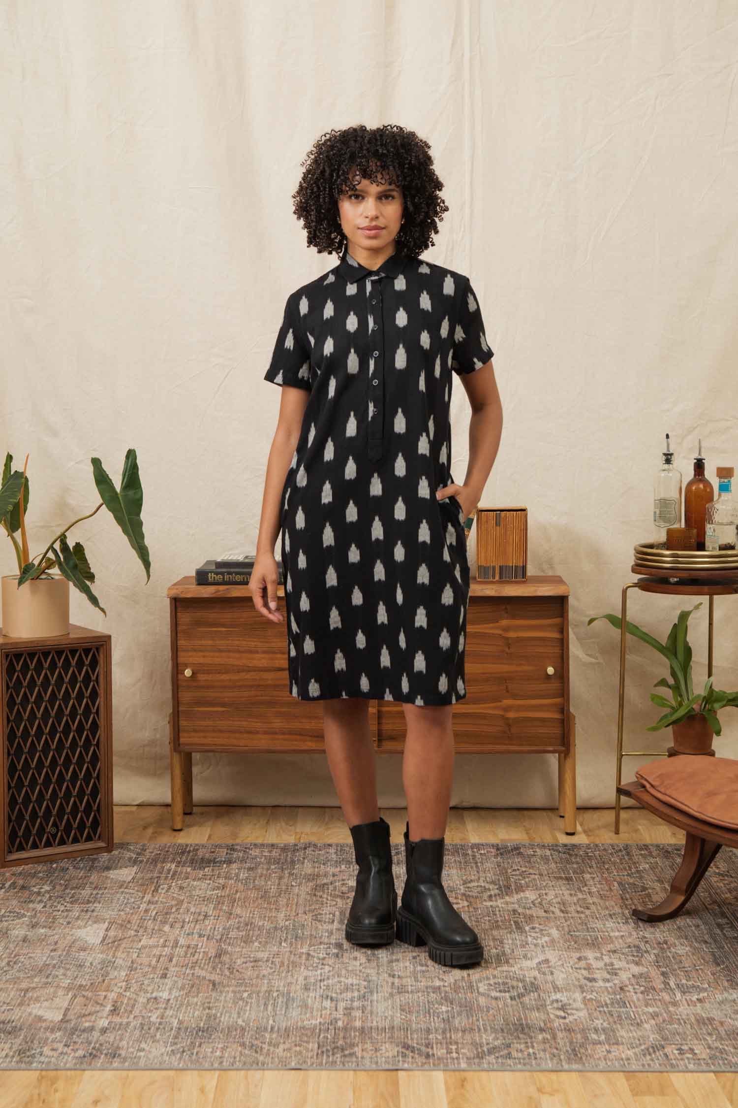 The Delia Shirt Dress in Eclipse Ikat by Bridge & Burn is a knee-length, black organic cotton dress with short sleeves, a collar, front buttons, and an allover white ikat pattern.