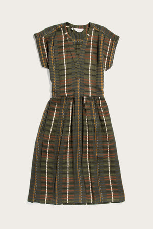 The Bridge & Burn Ira Dress in Olive Stripe is a short-sleeve, knee-length pullover with a V-neck and fitted waist, made from a modal-linen blend featuring dark green, brown, white, and rust plaid stripes.