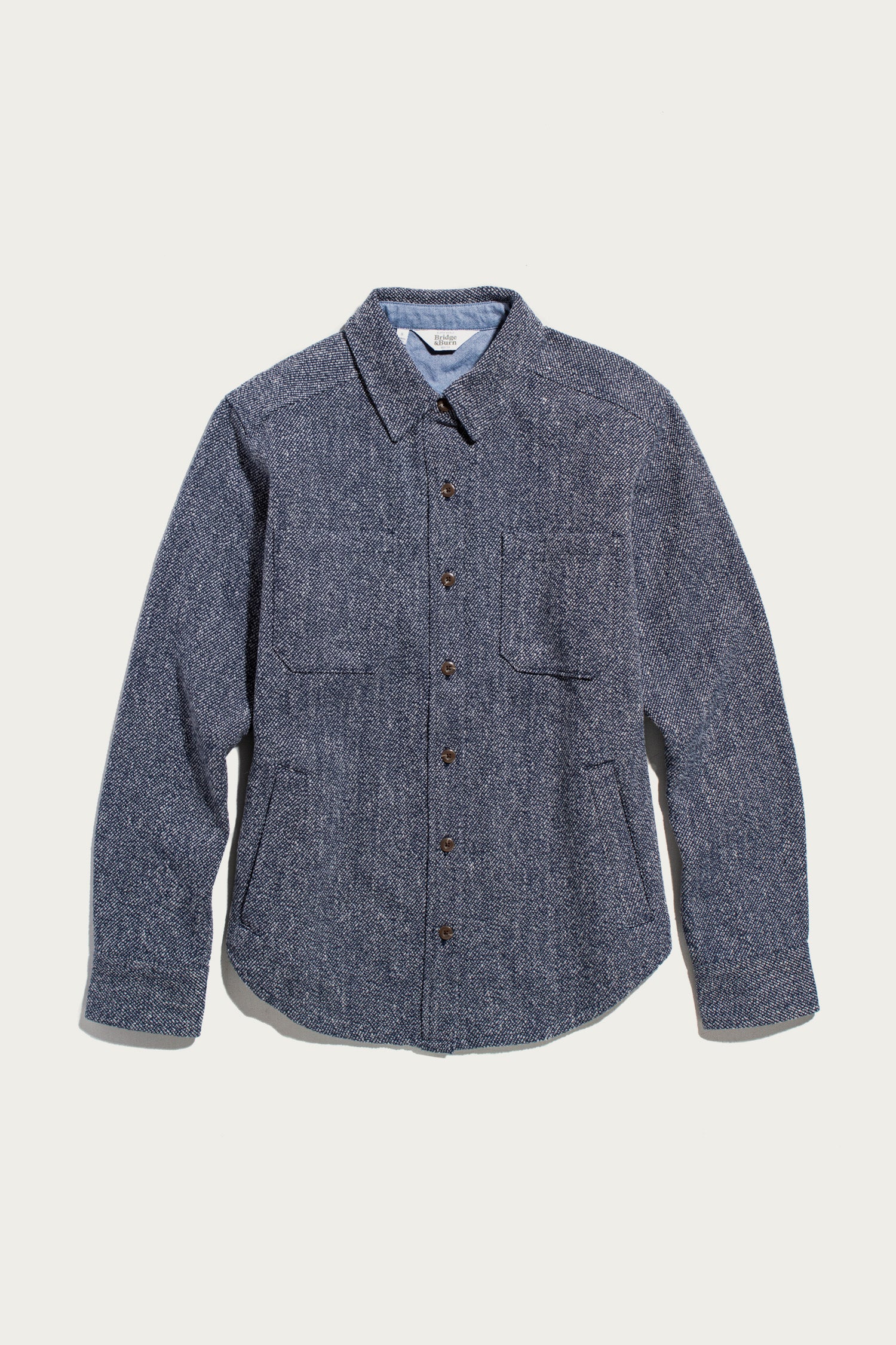 The Bridge & Burn Dawson Overshirt in Ocean Marl, featuring a blue textured design with two chest pockets and long sleeves, is crafted from recycled cotton for a sustainable choice and is shown laid flat on a white background.