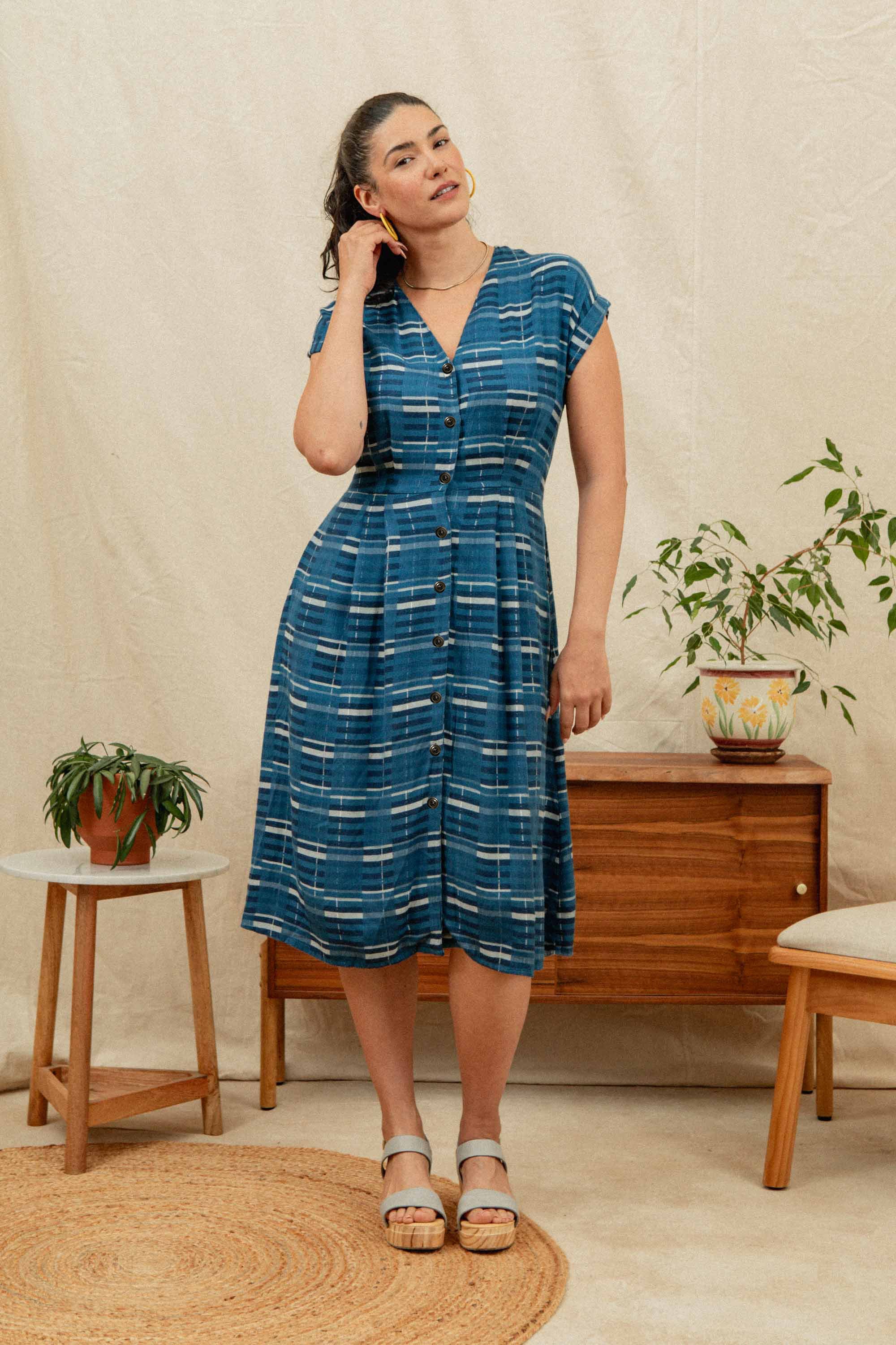 The Eileen Dress by Bridge & Burn in Stormcrest Stripe is a blue fit-and-flare with short sleeves, knee-length A-line skirt, white and navy plaid pattern, front buttons, V-neckline, and a slightly gathered waist.