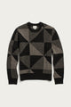 The Bridge & Burn Hollis Sweater / Stone Gale is a geometric-patterned crew neck sweater in black and gray, featuring triangles and rectangles. Crafted from soft Merino wool for style and comfort, it includes long sleeves with ribbed cuffs, collar, and hem, shown laid flat on a white background.