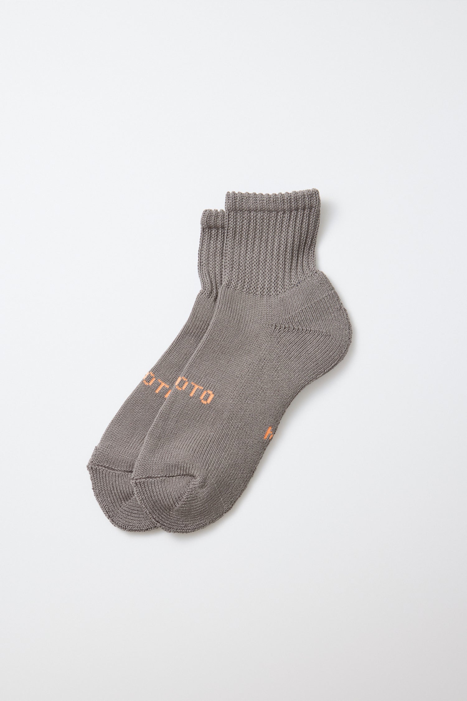 A pair of RoToTo Everyday Pile Ankle Socks in dark gray, crafted from organic cotton with ribbed cuffs and small orange text on the sides, made in Japan and displayed on a plain white background.