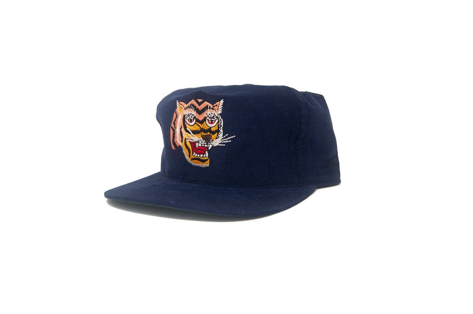The Ampal Creative - Tiger III Snapback / Navy: A navy blue corduroy cap with an embroidered tiger face on the front, inspired by Vietnam era Souvenir Jacket designs, from The Ampal Creative. Displayed against a plain white background.
